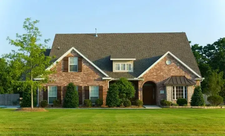 A two-story brick home with brown shutters and a well-maintained lawn after new window installation in Springfield.